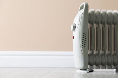 Photo of Electric heater on floor near beige wall indoors, closeup. Space for text
