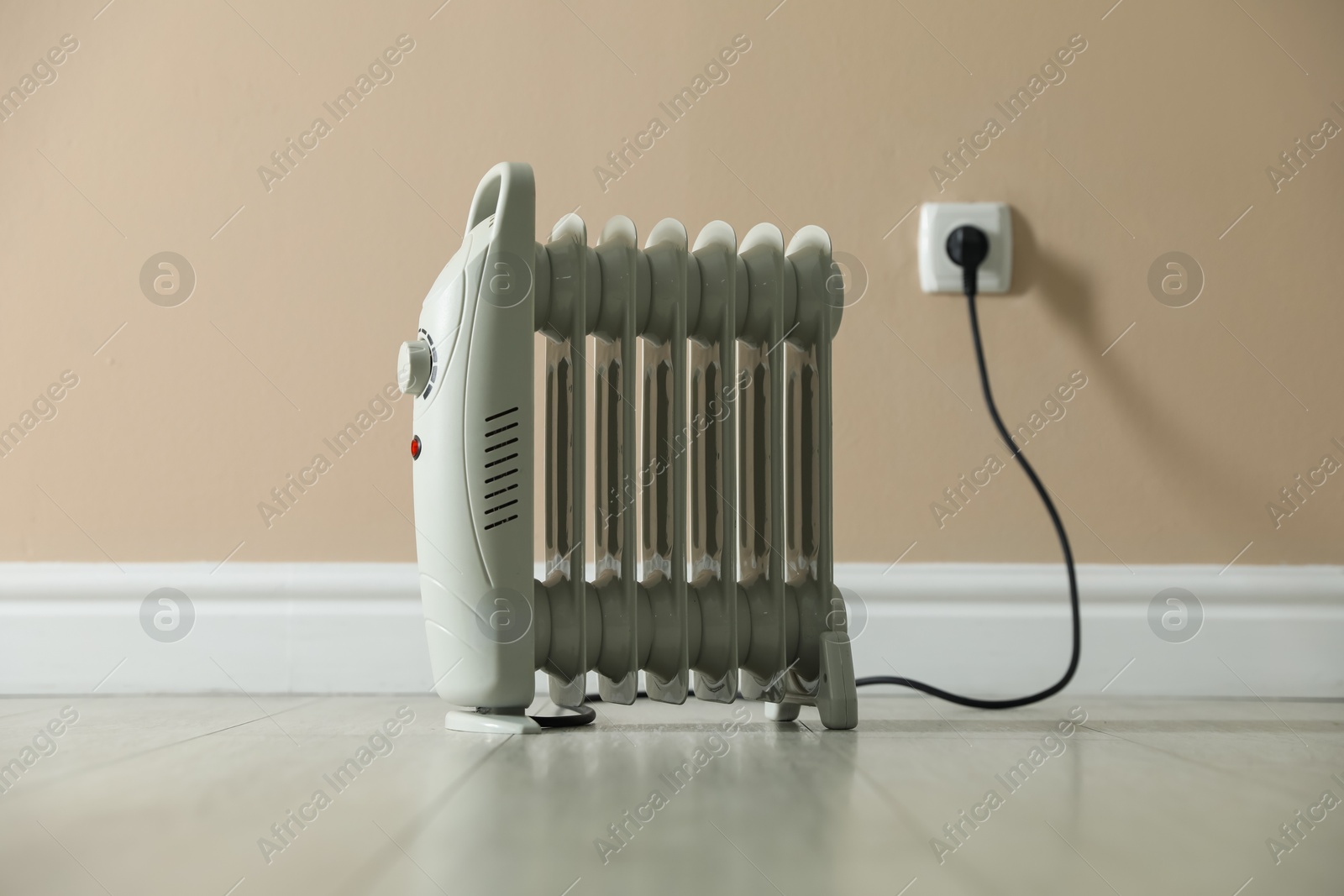 Photo of Electric heater on floor near beige wall indoors
