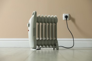Photo of Electric heater on floor near beige wall indoors