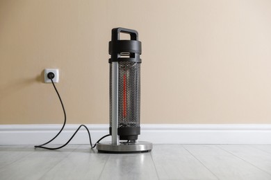 Photo of Electric heater on floor near beige wall indoors