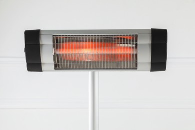 Photo of Electric infrared heater near white wall indoors, closeup