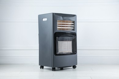 Photo of Electric heater on floor near light grey wall indoors