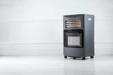 Photo of Electric heater on floor near light grey wall indoors. Space for text
