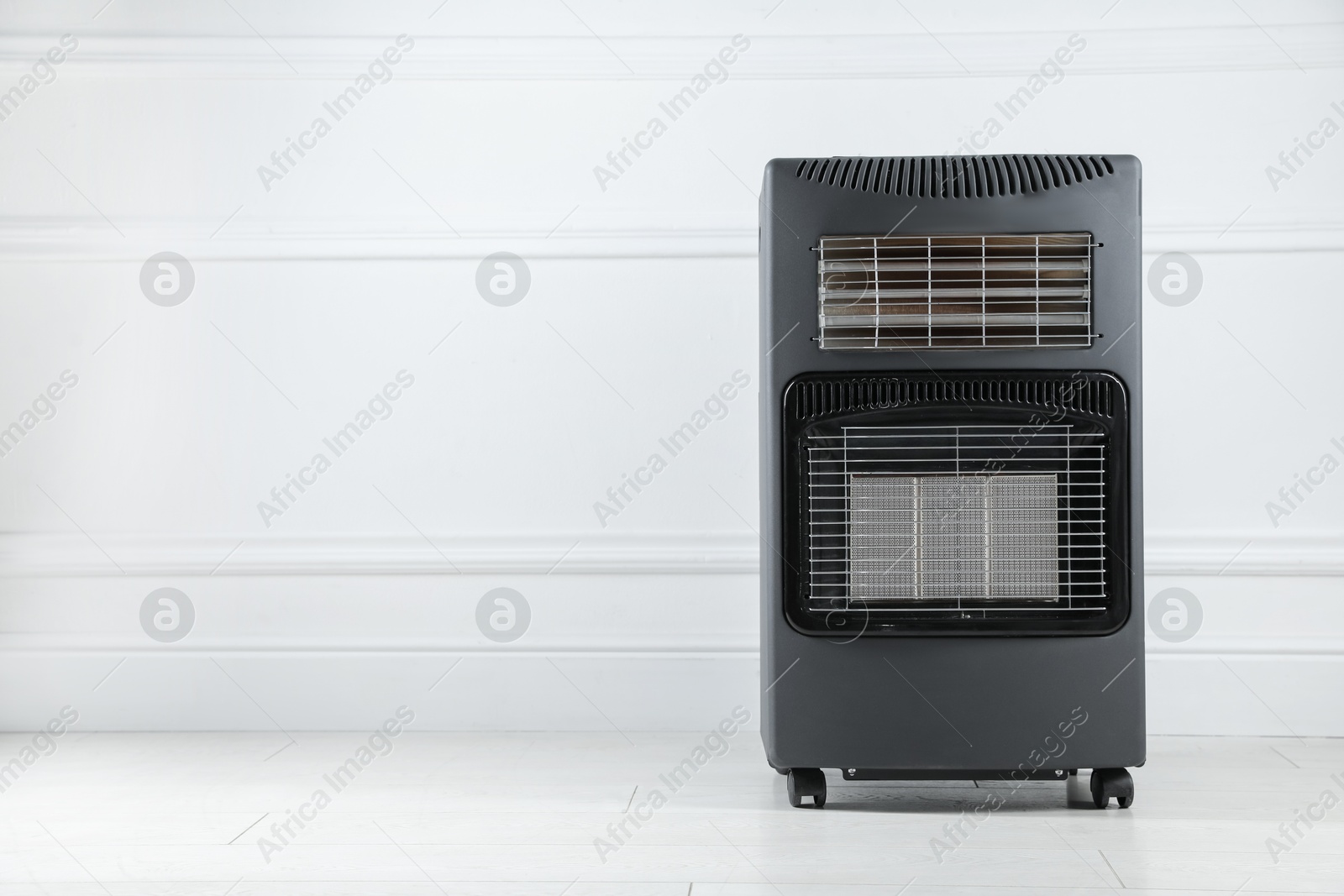 Photo of Electric heater on floor near light wall indoors. Space for text