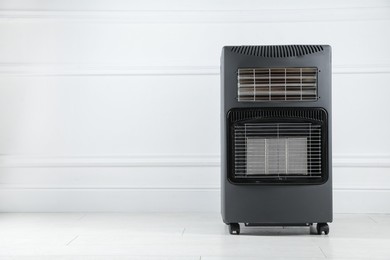 Photo of Electric heater on floor near light wall indoors. Space for text