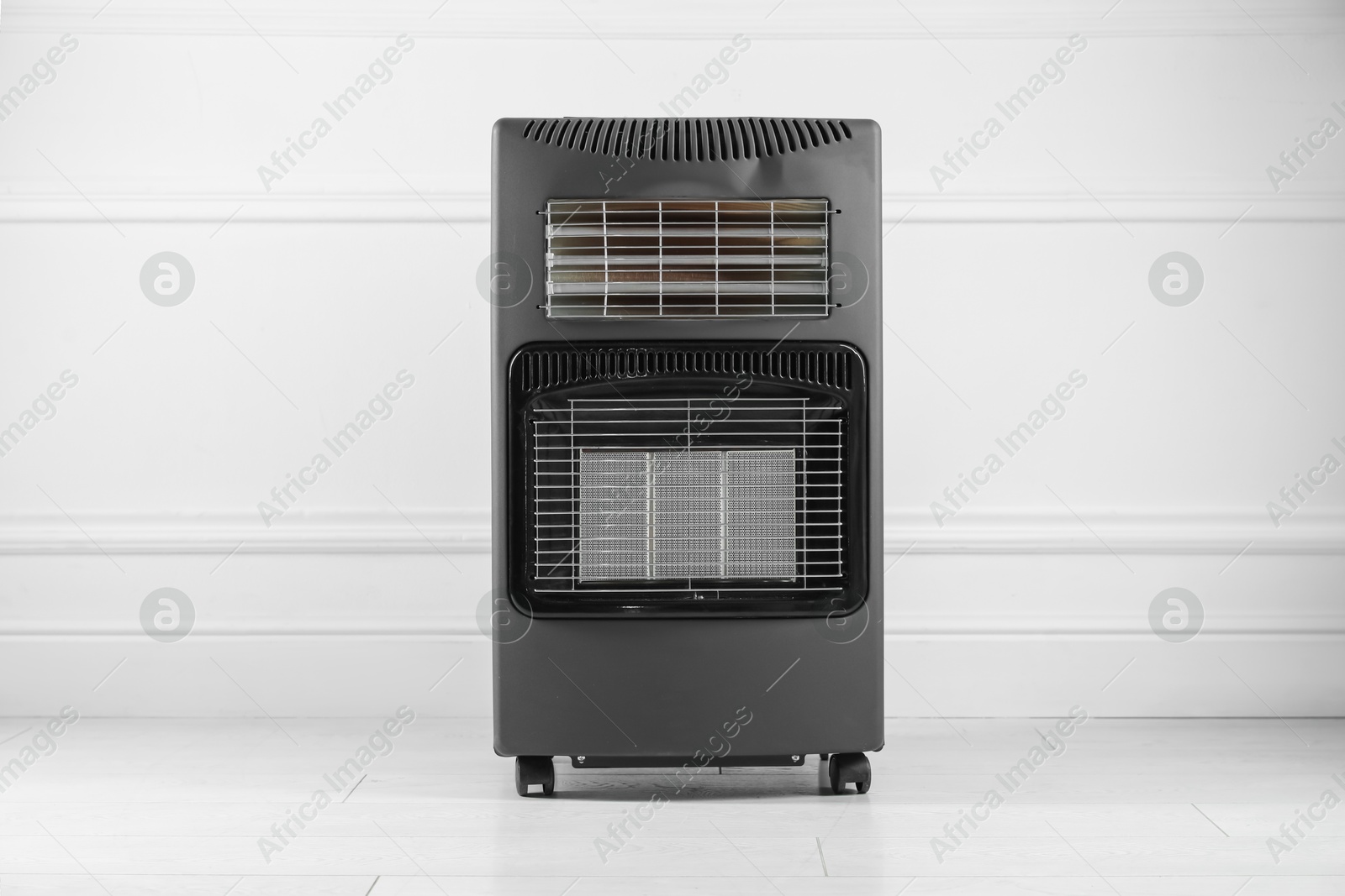 Photo of Electric heater on floor near light grey wall indoors