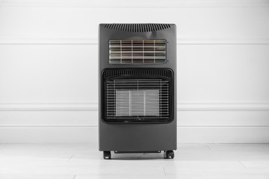 Photo of Electric heater on floor near light grey wall indoors