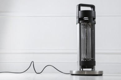 Photo of Electric heater on floor near light grey wall indoors. Space for text