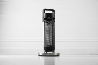 Photo of Electric heater on floor near light grey wall indoors