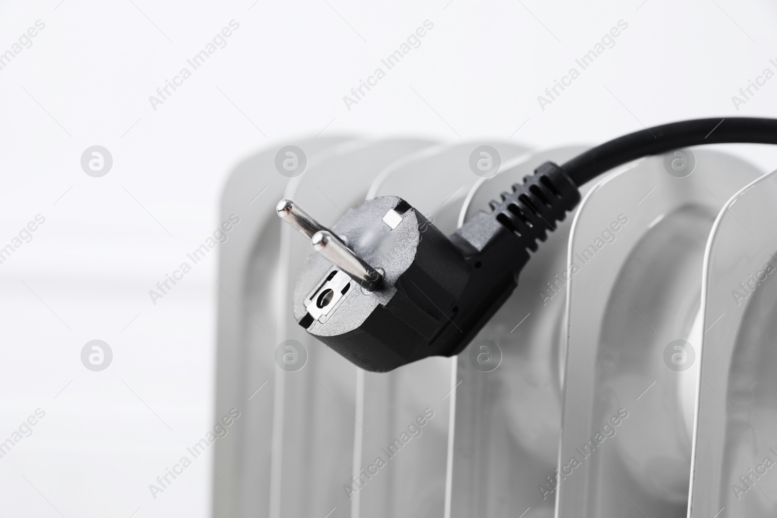 Photo of Electric heater and plug against blurred light background, closeup. Space for text