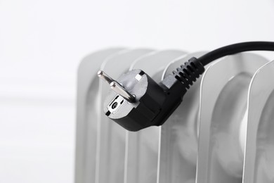 Photo of Electric heater and plug against blurred light background, closeup. Space for text