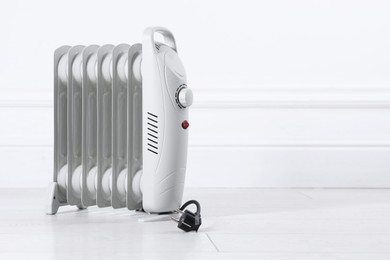 Photo of Electric heater on floor near light wall indoors. Space for text
