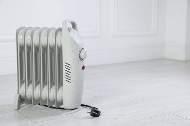 Photo of Electric heater on floor near light grey wall indoors. Space for text