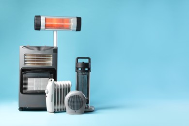 Photo of Different electric heaters on light blue background. Space for text