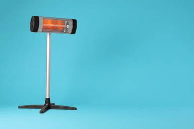 Photo of Electric infrared heater on light blue background. Space for text