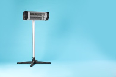 Photo of Electric infrared heater on light blue background. Space for text
