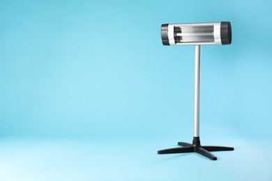 Photo of Electric infrared heater on light blue background. Space for text