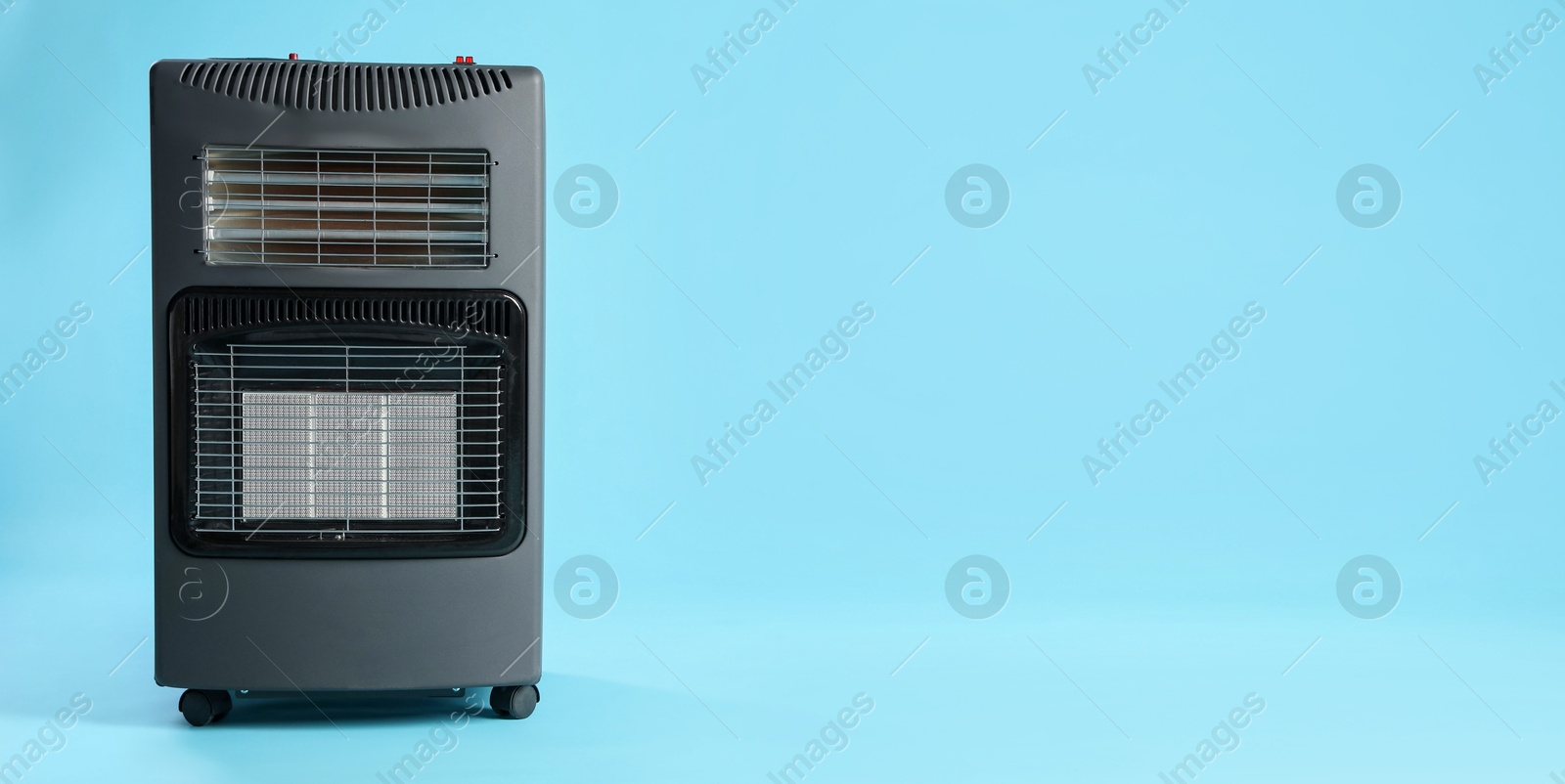 Photo of Electric heater on light blue background. Space for text
