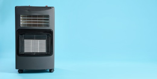 Photo of Electric heater on light blue background. Space for text