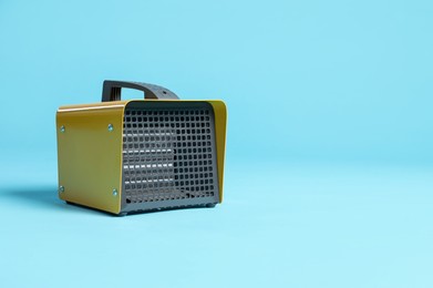 Photo of Electric fan heater on light blue background. Space for text