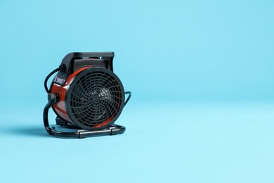 Photo of Electric fan heater on light blue background. Space for text