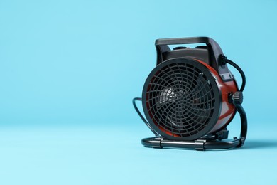 Photo of Electric fan heater on light blue background. Space for text