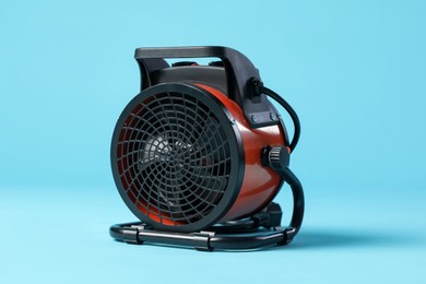 Photo of Electric fan heater on light blue background, closeup