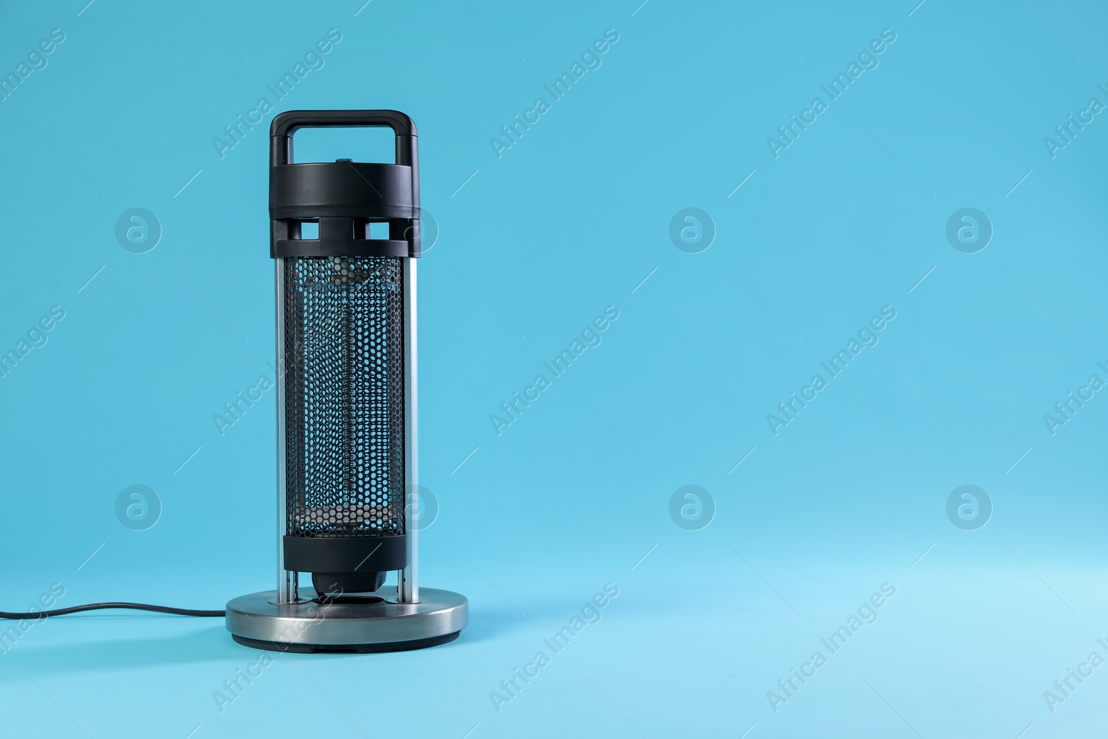 Photo of Electric heater on light blue background. Space for text