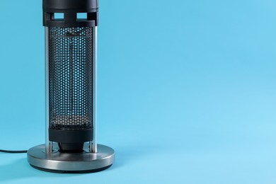 Photo of Electric heater on light blue background, closeup. Space for text