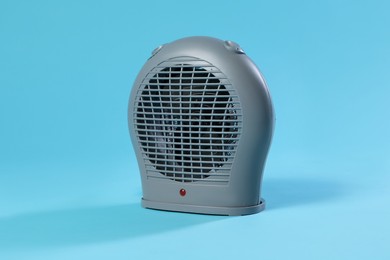 Photo of Electric fan heater on light blue background, closeup