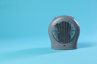 Photo of Electric fan heater on light blue background. Space for text