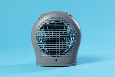 Photo of Electric fan heater on light blue background, closeup