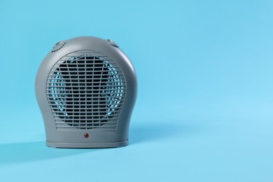 Photo of Electric fan heater on light blue background. Space for text