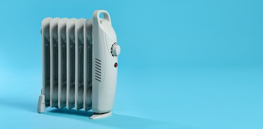 Photo of Electric heater on light blue background. Space for text