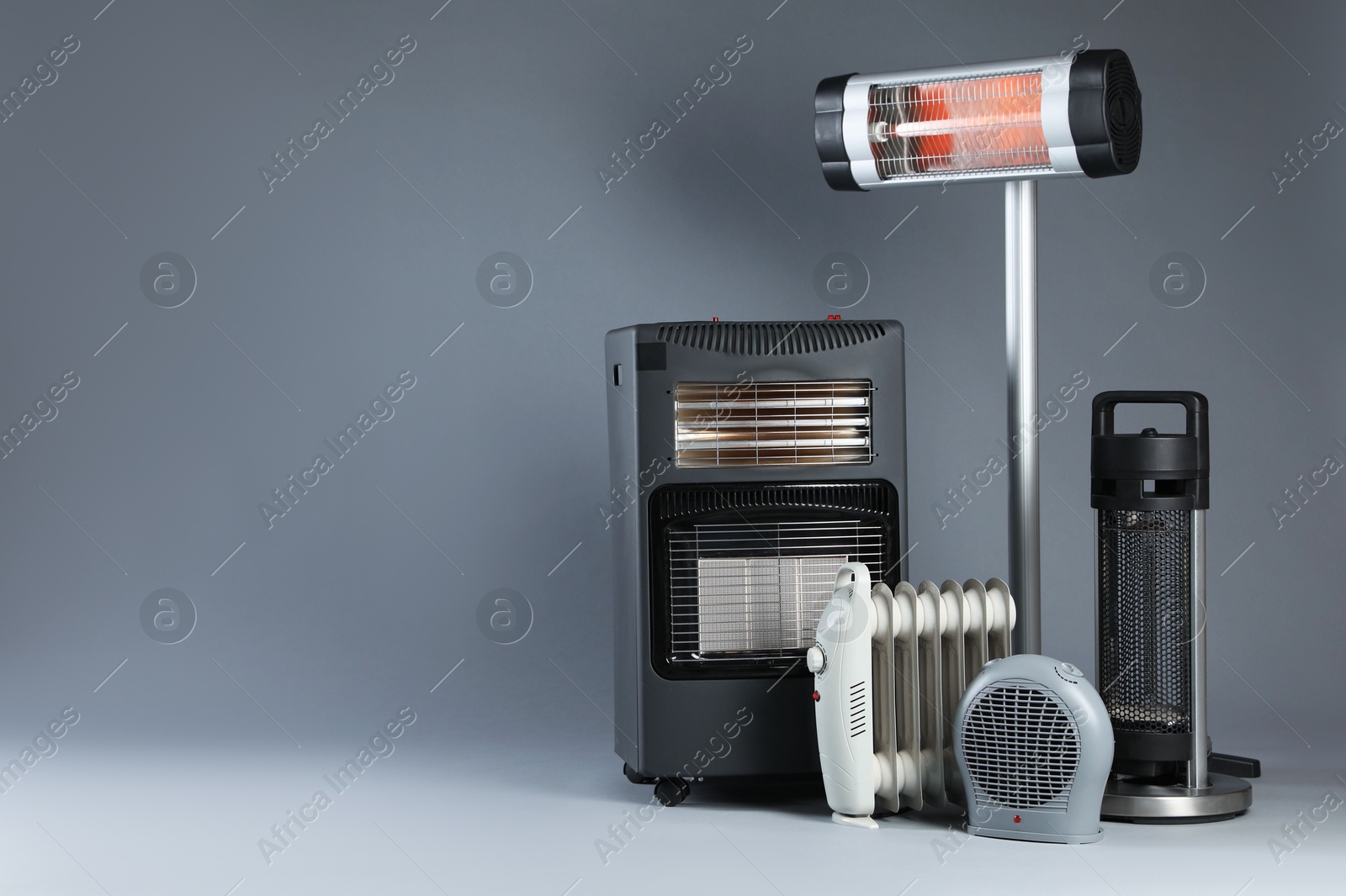 Photo of Different electric heaters on grey background. Space for text