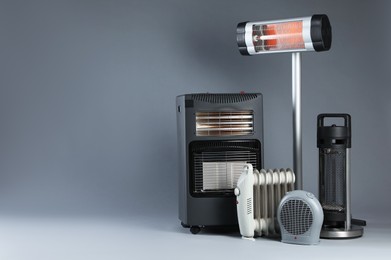 Photo of Different electric heaters on grey background. Space for text