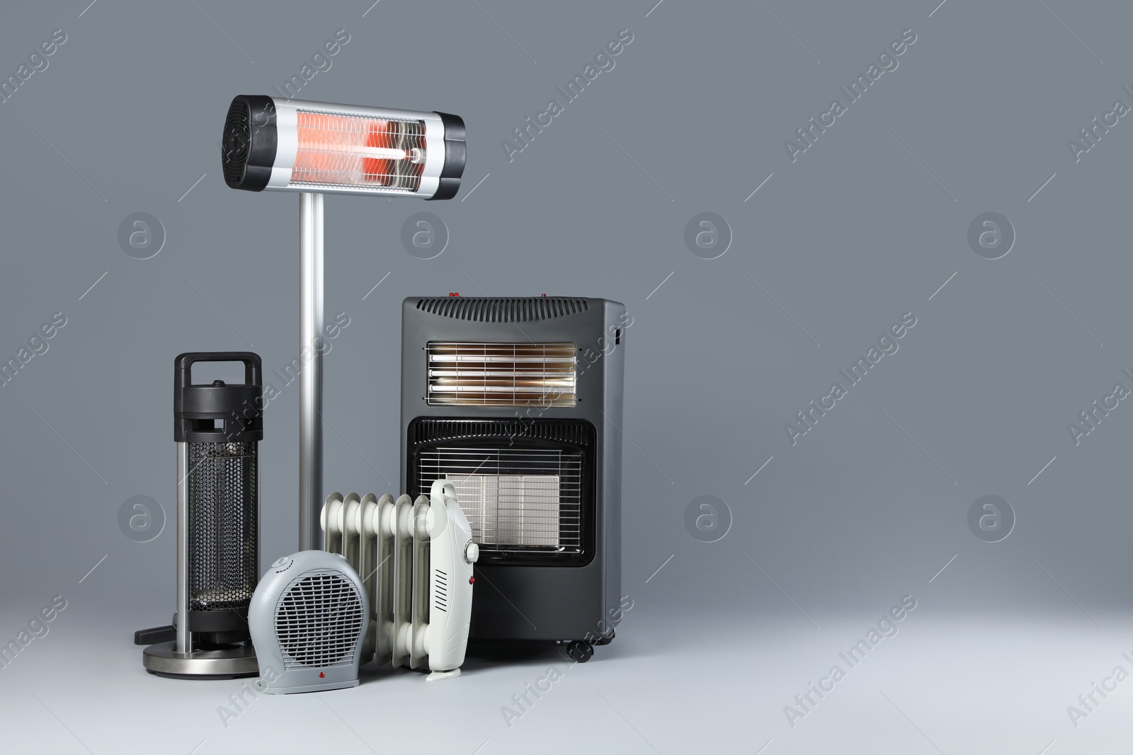 Photo of Different electric heaters on grey background. Space for text