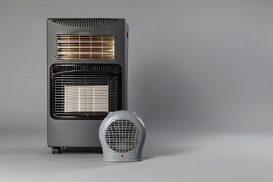 Photo of Different types of electric heaters on grey background. Space for text
