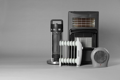 Photo of Different electric heaters on grey background. Space for text