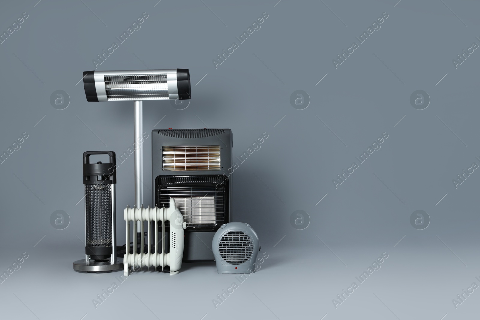 Photo of Different electric heaters on grey background. Space for text