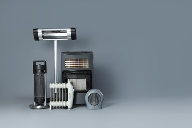 Photo of Different electric heaters on grey background. Space for text