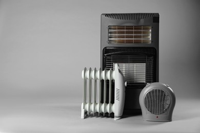 Photo of Different types of electric heaters on grey background. Space for text