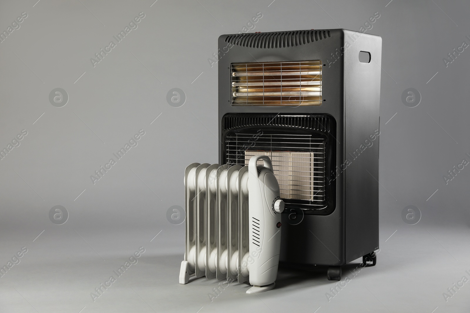 Photo of Different types of electric heaters on grey background. Space for text