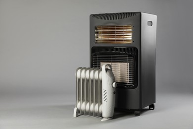 Photo of Different types of electric heaters on grey background. Space for text