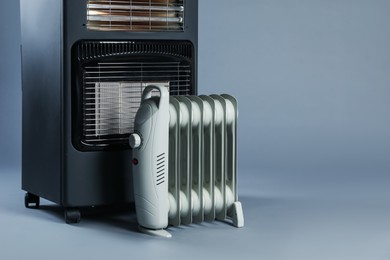 Photo of Different types of electric heaters on grey background. Space for text
