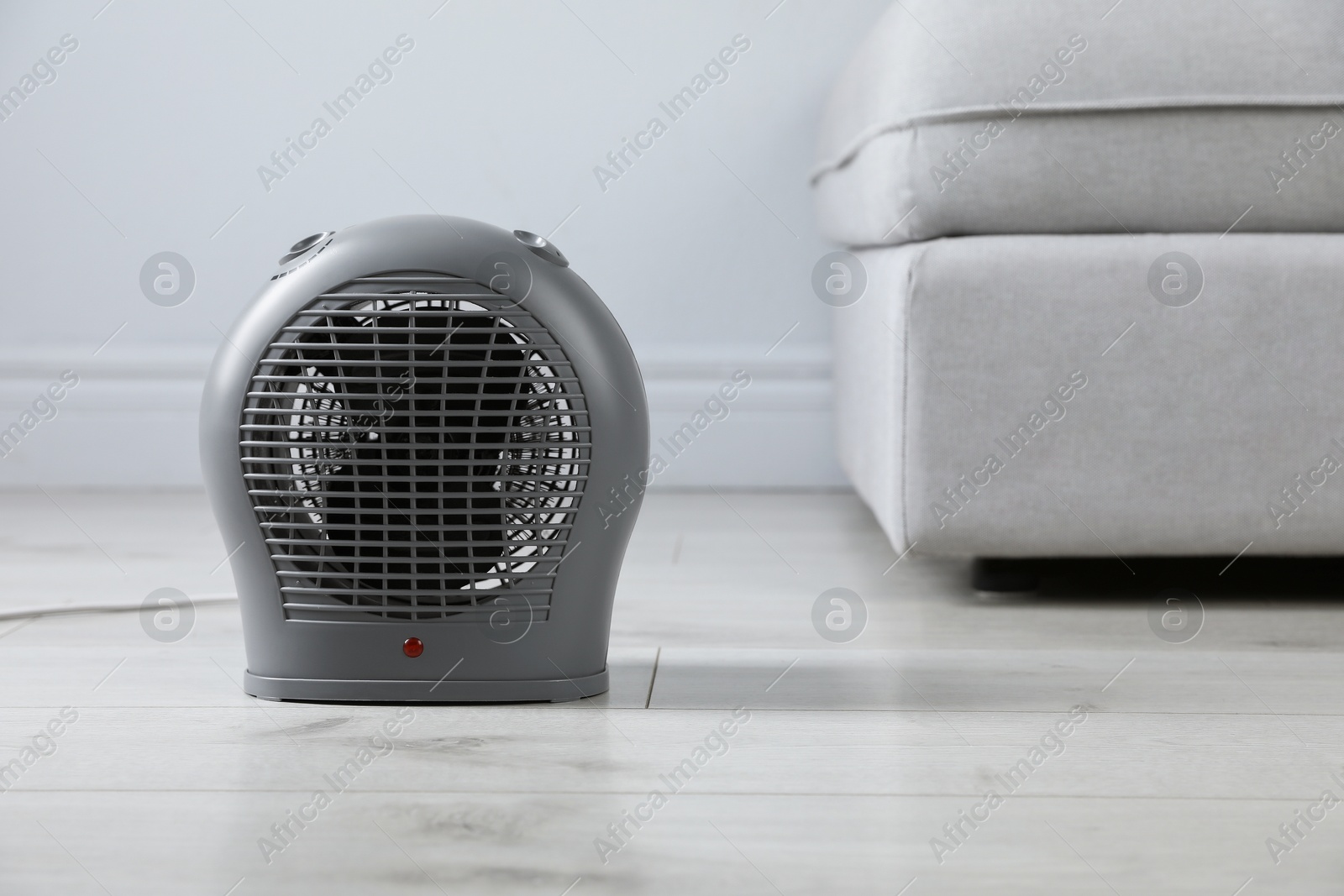 Photo of Electric fan heater on light wooden floor indoors. Space for text