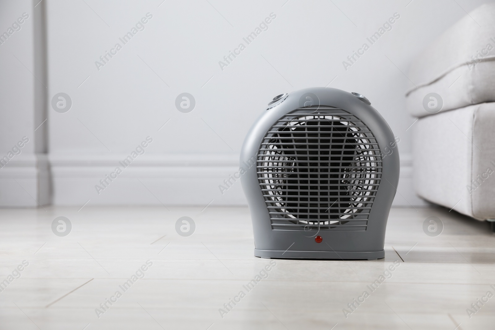 Photo of Electric fan heater on light wooden floor indoors. Space for text