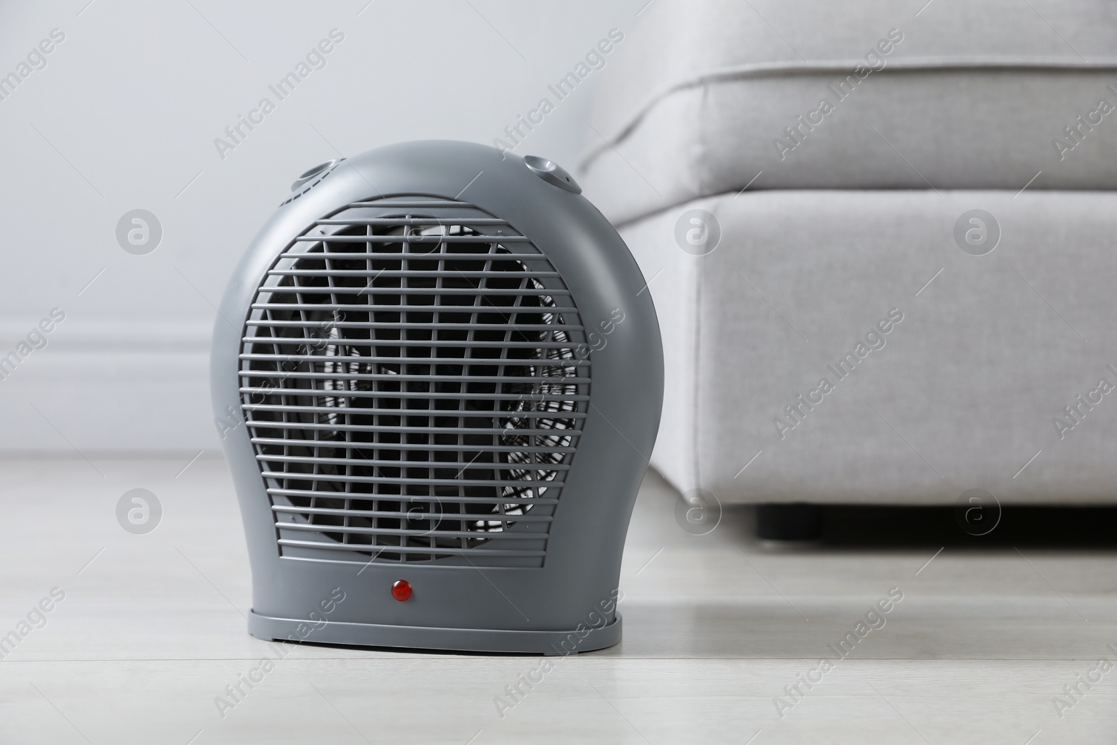 Photo of Electric fan heater on light wooden floor indoors, closeup. Space for text