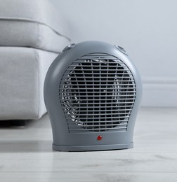 Photo of Electric fan heater on light wooden floor indoors, closeup