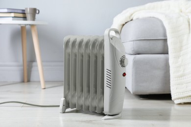 Photo of Electric heater on light wooden floor indoors